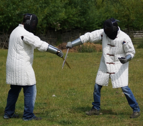Image shows two people in protective gear staging a realistic sword fighting sequence using specially commissioned replica Bronze Age weapons